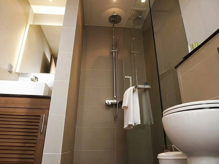 Bathroom with glass-enclosed shower, sink and toilet at Sukhumvit Suites Hotel Bangkok