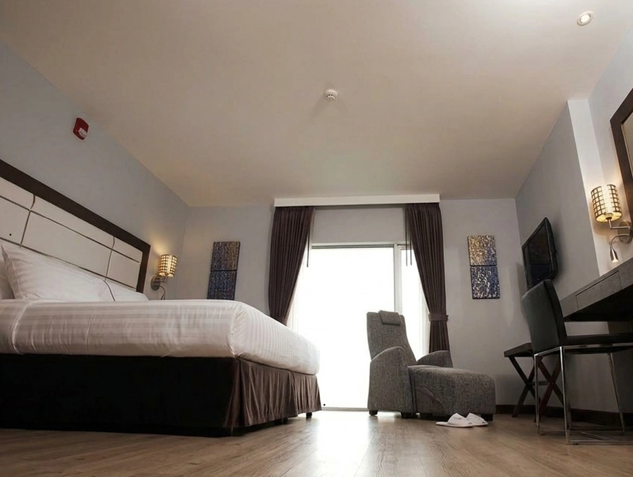 Double guestroom with bed, armchair, desk and window at Sukhumvit Suites Hotel Bangkok
